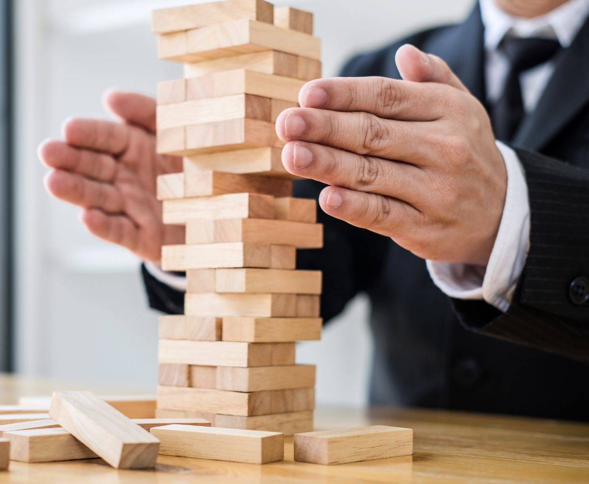 empresario intenta que no se caiga una torre hecha con bloques de madera